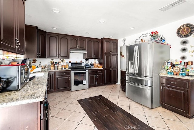 kitchen with light stone counters, dark brown cabinets, stainless steel appliances, and light tile patterned flooring