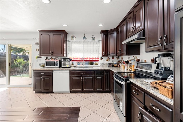 kitchen featuring light tile patterned flooring, appliances with stainless steel finishes, sink, light stone counters, and dark brown cabinetry