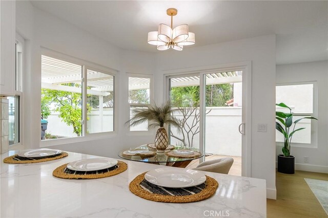 dining area with baseboards, light wood finished floors, and a chandelier