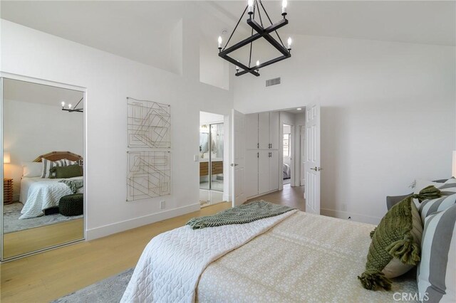 bedroom featuring a notable chandelier, light wood-style floors, visible vents, and baseboards