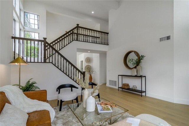 living room featuring visible vents, baseboards, a high ceiling, and wood finished floors