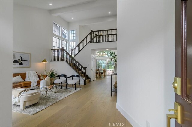 foyer featuring baseboards, plenty of natural light, light wood-style floors, and stairs