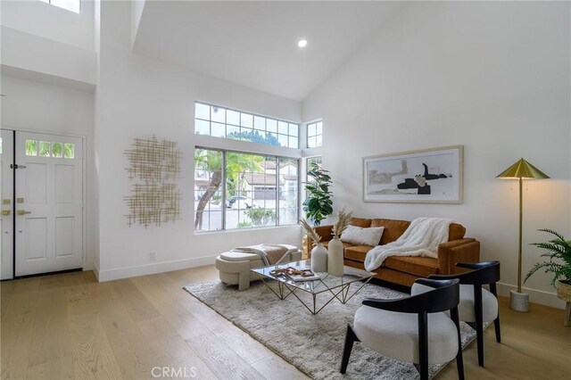 living room with recessed lighting, baseboards, light wood-type flooring, and high vaulted ceiling