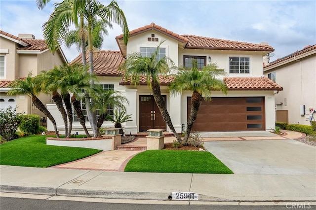 mediterranean / spanish-style home featuring a garage and a front yard