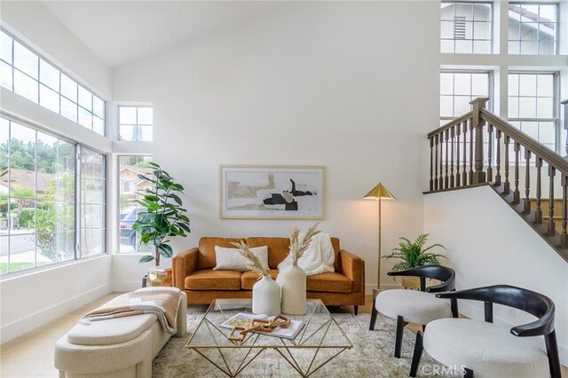 living area with a wealth of natural light, high vaulted ceiling, baseboards, and wood finished floors