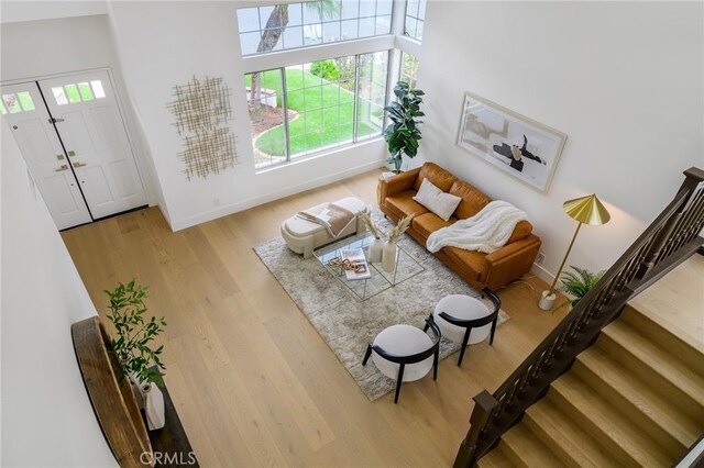 living room with stairs, wood finished floors, and baseboards