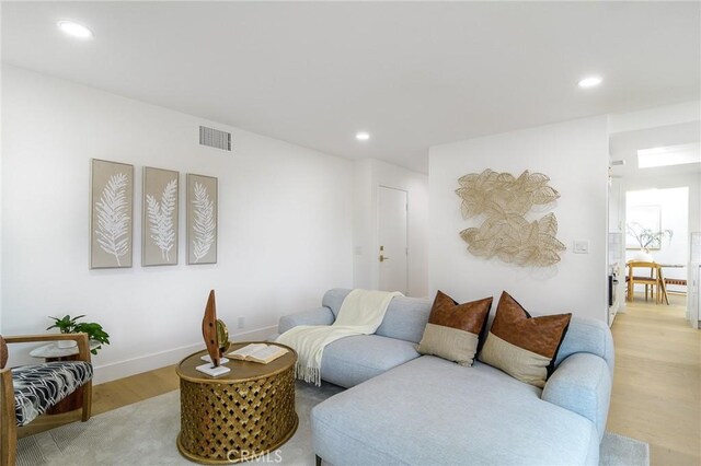 living room featuring light wood-type flooring, visible vents, and recessed lighting