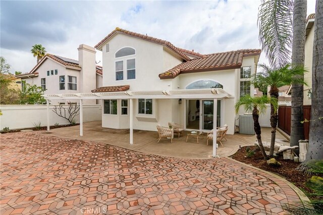 rear view of property with a patio area, a tile roof, stucco siding, and fence