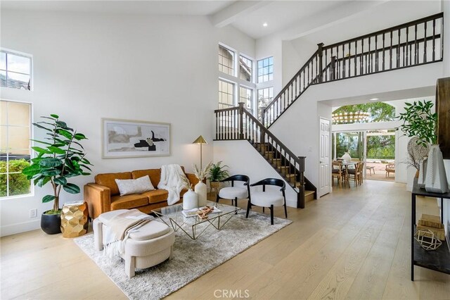 living room with plenty of natural light, beamed ceiling, a high ceiling, and wood finished floors