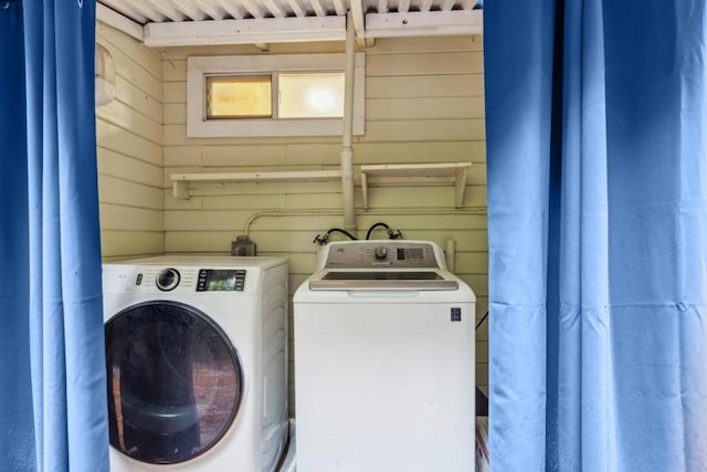 clothes washing area with washing machine and dryer and wooden walls