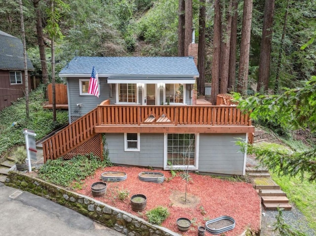 back of house with a wooden deck and a fire pit