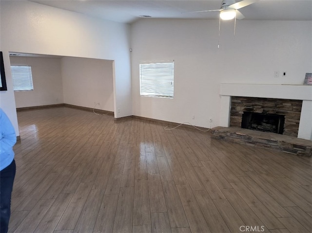 unfurnished living room with a stone fireplace, hardwood / wood-style floors, and ceiling fan