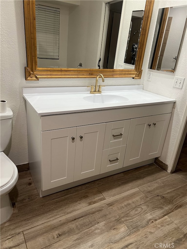 bathroom with hardwood / wood-style flooring, vanity, and toilet