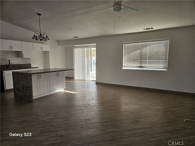 kitchen featuring dark wood-type flooring, white cabinetry, tasteful backsplash, decorative light fixtures, and a kitchen island