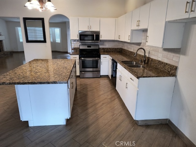 kitchen featuring appliances with stainless steel finishes, dark hardwood / wood-style floors, white cabinetry, sink, and dark stone counters