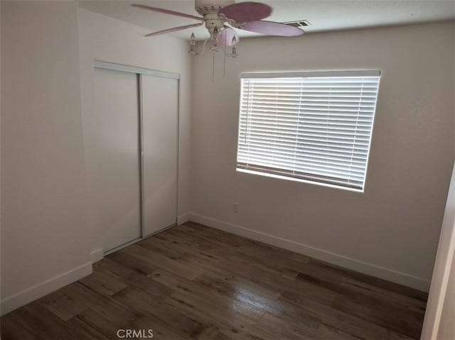 unfurnished bedroom featuring dark hardwood / wood-style flooring, ceiling fan, and a closet