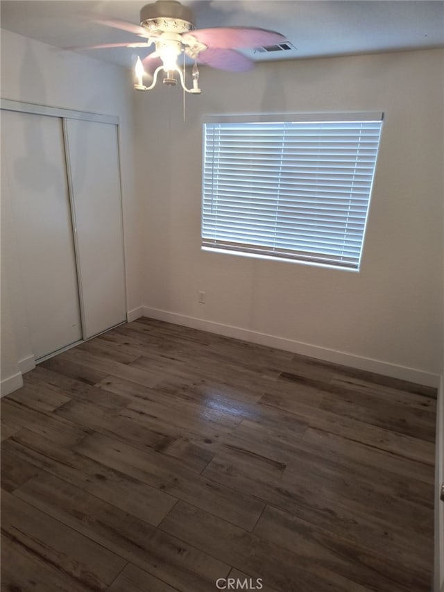 unfurnished bedroom featuring dark wood-type flooring, ceiling fan, and a closet