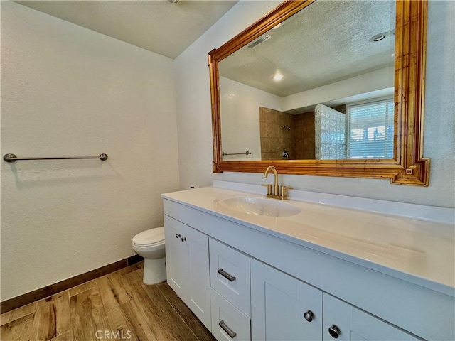 bathroom with hardwood / wood-style flooring, vanity, walk in shower, toilet, and a textured ceiling