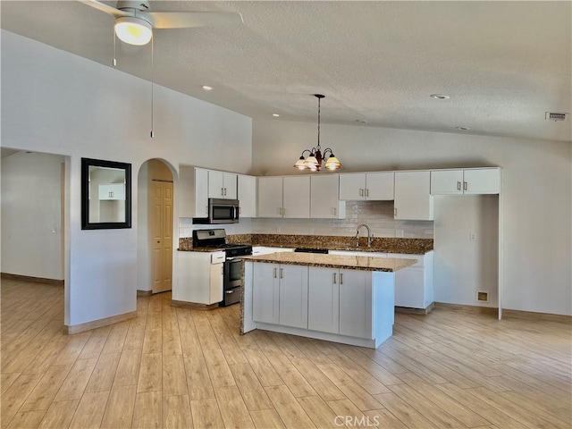 kitchen with white cabinetry, decorative light fixtures, a kitchen island, stainless steel appliances, and light hardwood / wood-style floors