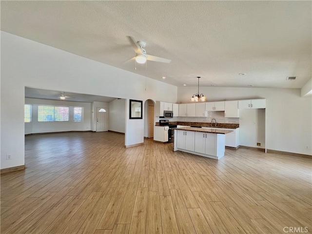 kitchen with light hardwood / wood-style flooring, white cabinetry, stainless steel appliances, a center island, and vaulted ceiling