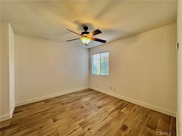 empty room with ceiling fan, hardwood / wood-style floors, and a textured ceiling