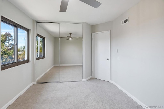 unfurnished bedroom featuring light colored carpet, a closet, and ceiling fan