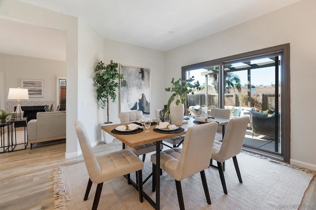 dining space featuring a tile fireplace and light wood-type flooring