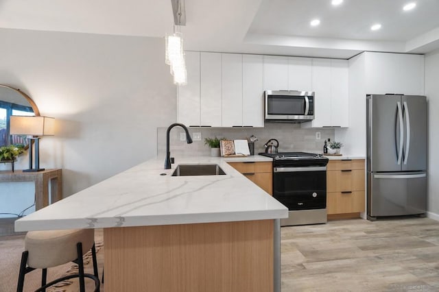 kitchen with appliances with stainless steel finishes, pendant lighting, sink, white cabinets, and decorative backsplash