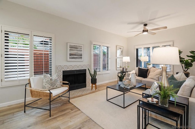 living room with a fireplace, light hardwood / wood-style flooring, a healthy amount of sunlight, and ceiling fan