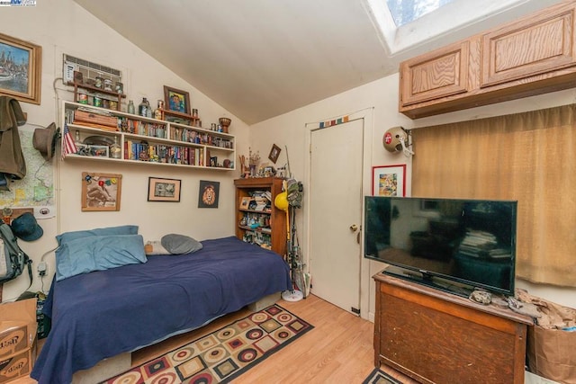 bedroom with lofted ceiling with skylight and light hardwood / wood-style floors