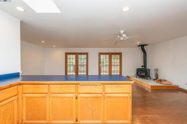 kitchen featuring a skylight, a wood stove, ceiling fan, dark wood-type flooring, and french doors