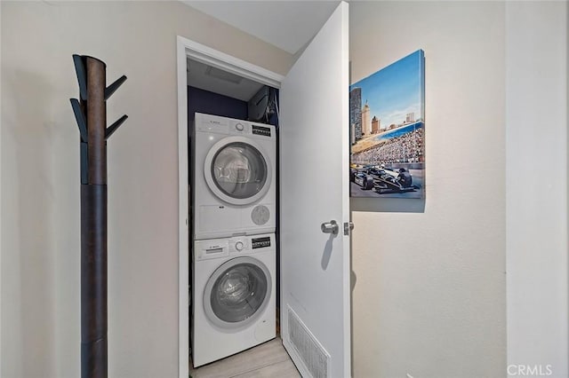 laundry area featuring light tile patterned floors and stacked washer and clothes dryer