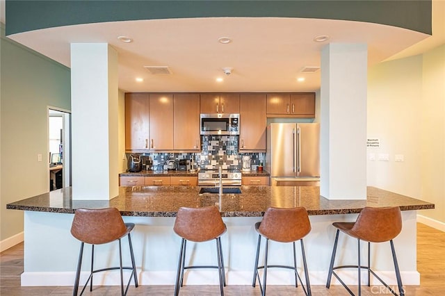 kitchen with stainless steel appliances, sink, a kitchen bar, and dark stone counters