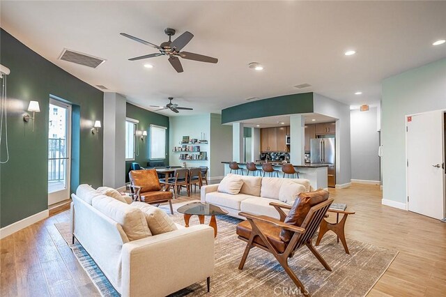 living room with light hardwood / wood-style flooring and ceiling fan