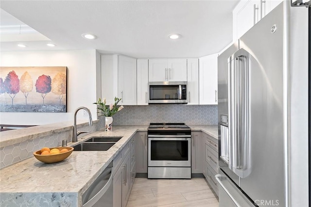 kitchen featuring sink, white cabinetry, light stone counters, appliances with stainless steel finishes, and backsplash