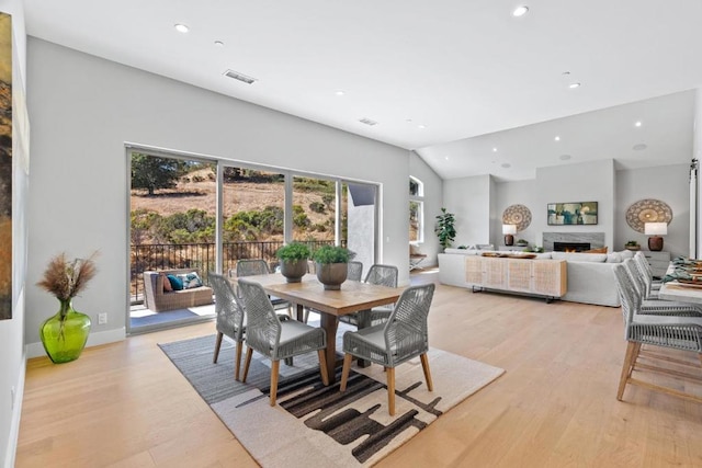 dining area featuring vaulted ceiling and light hardwood / wood-style floors