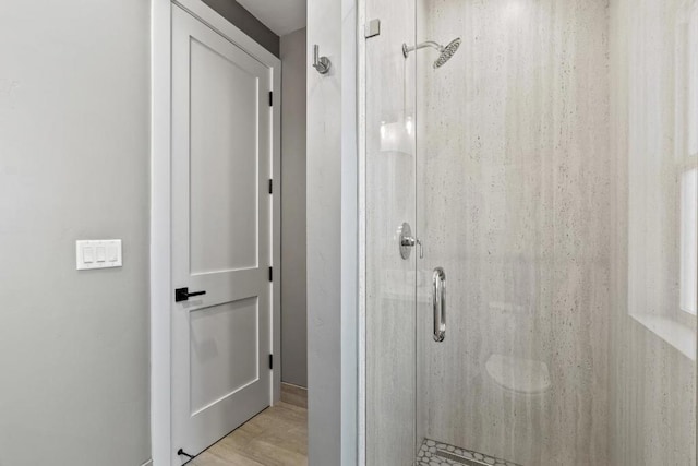 bathroom with wood-type flooring and an enclosed shower