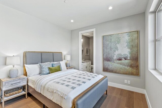 bedroom with hardwood / wood-style flooring and ensuite bath