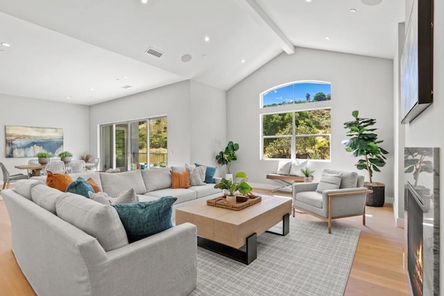 living room featuring vaulted ceiling with beams and light wood-type flooring