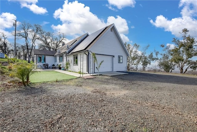 back of property featuring a garage and solar panels