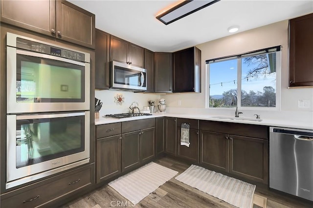 kitchen featuring appliances with stainless steel finishes, dark hardwood / wood-style flooring, sink, and dark brown cabinets