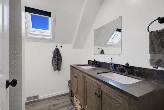 bathroom featuring vanity, vaulted ceiling with skylight, and hardwood / wood-style floors