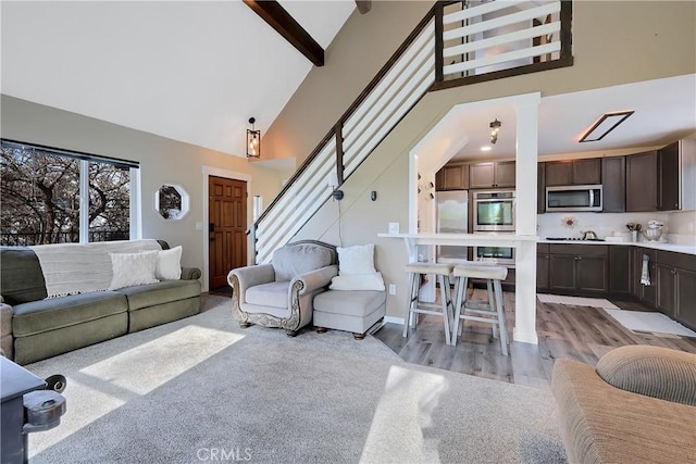 living room featuring beamed ceiling, light hardwood / wood-style floors, high vaulted ceiling, and ornate columns