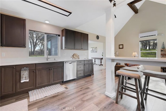 kitchen featuring dishwasher, sink, light hardwood / wood-style floors, dark brown cabinets, and beam ceiling