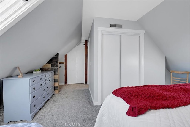 bedroom with a closet, lofted ceiling, and light carpet