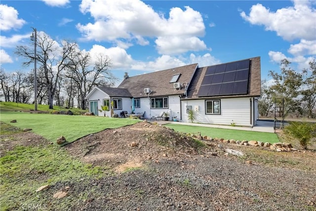 rear view of house with a lawn and solar panels