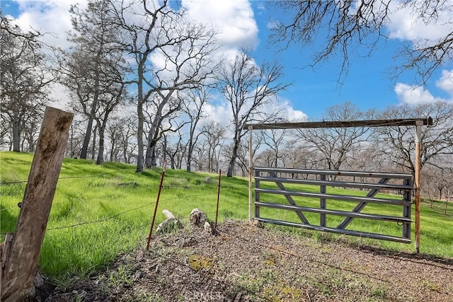 view of gate featuring a rural view and a lawn