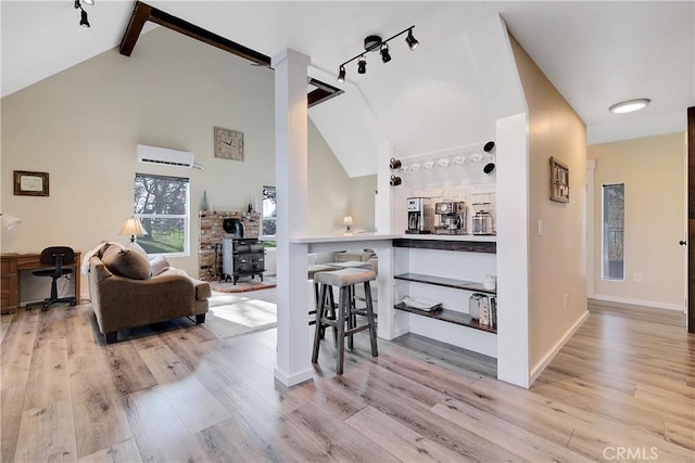 interior space featuring lofted ceiling with beams, a wall mounted air conditioner, and light hardwood / wood-style floors