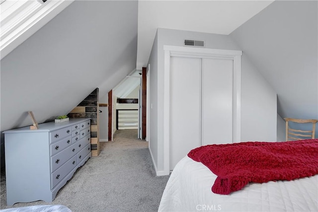 bedroom featuring a closet, lofted ceiling, and light carpet