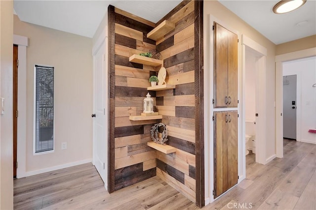 hall with wooden walls and light hardwood / wood-style flooring